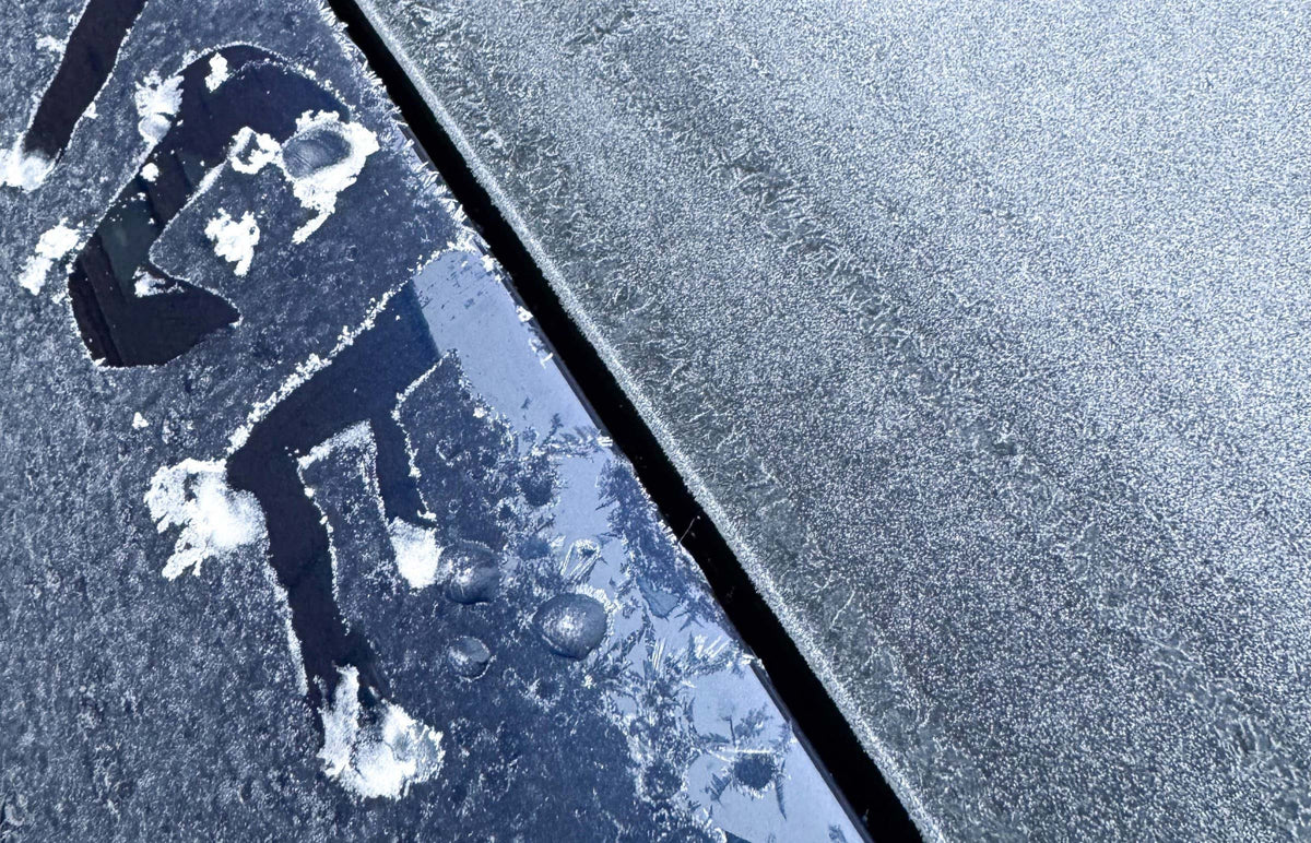 Frostiga stenplattor med en figur ritad i frosten bredvid en mörk fog